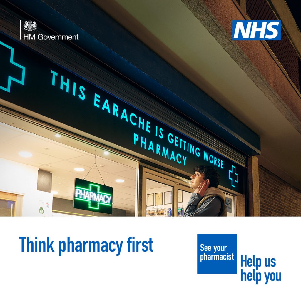 A person is standing outside a pharmacy holding the side of their face in discomfort. The sign above the pharmacy reads 'This earache is getting worse pharmacy'

 A lower third box features in the bottom on the image. Text in the box reads: 'Think pharmacy first'