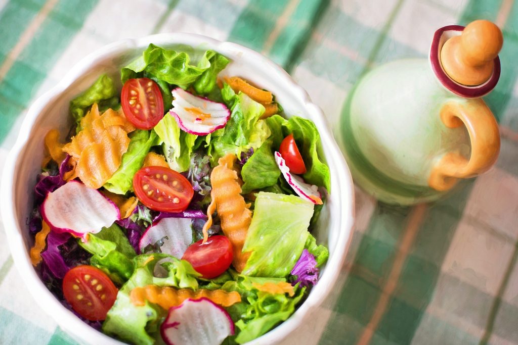 A bowl of mixed salad is shown on a checked table cloth